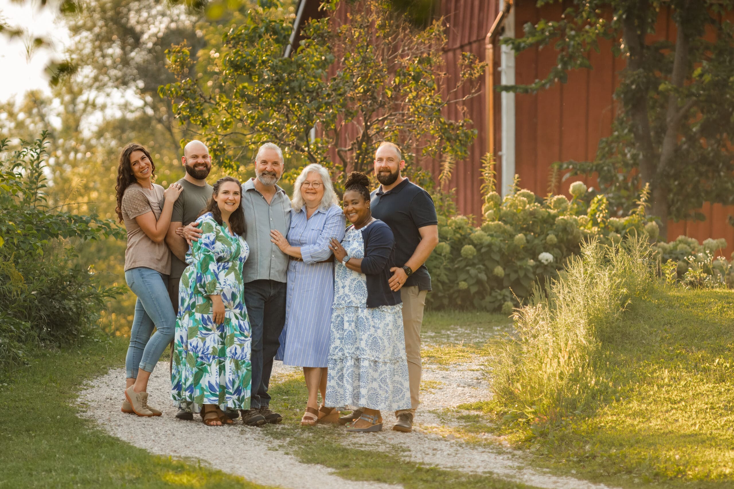 An extended family photo session in the summer with a beautiful red barn in the background, taken by Laura Lu Photography, LLC.